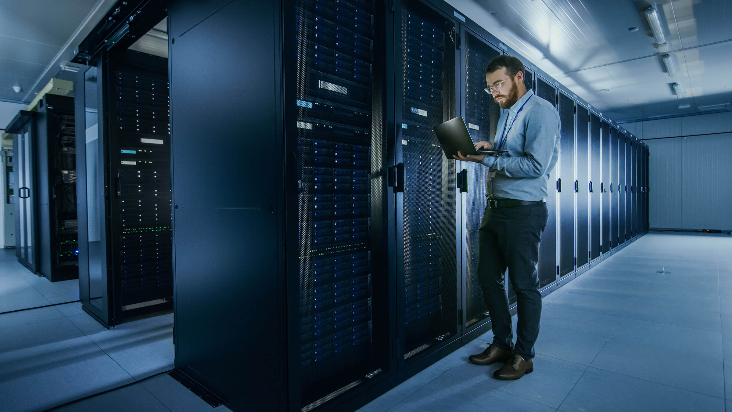 Male IT professional on laptop in server room